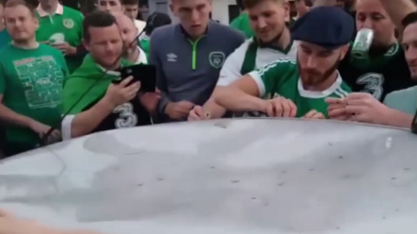 Con cerveza y cánticos hinchas irlandeses intentan reparar un auto que habían dañado