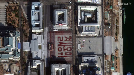 FOTO: Miles de norcoreanos crean con sus cuerpos la frase "defender con su vida" durante el ensayo de un desfile