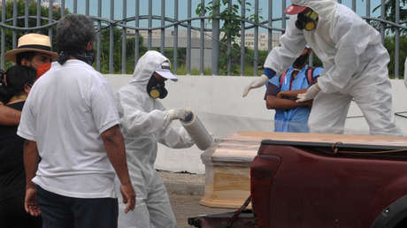 Familiares de pacientes con covid-19 oran de rodillas frente al hospital Guasmo Sur, uno de los más afectados por la pandemia en Ecuador