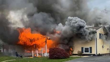 Una mujer prende fuego a su casa con una persona adentro y se sienta a ver la escena desde una silla en el jardín (VIDEO)