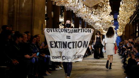 Una activista irrumpe en un desfile de moda de Louis Vuitton en París y exhibe un cartel en la pasarela (VIDEO)
