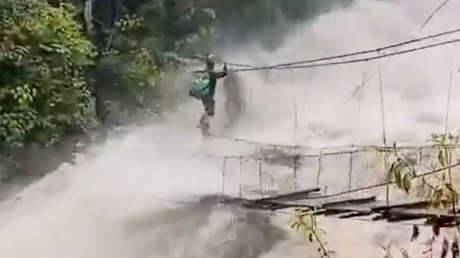 VIDEO: Cruza un río embravecido aferrado a un puente colgante